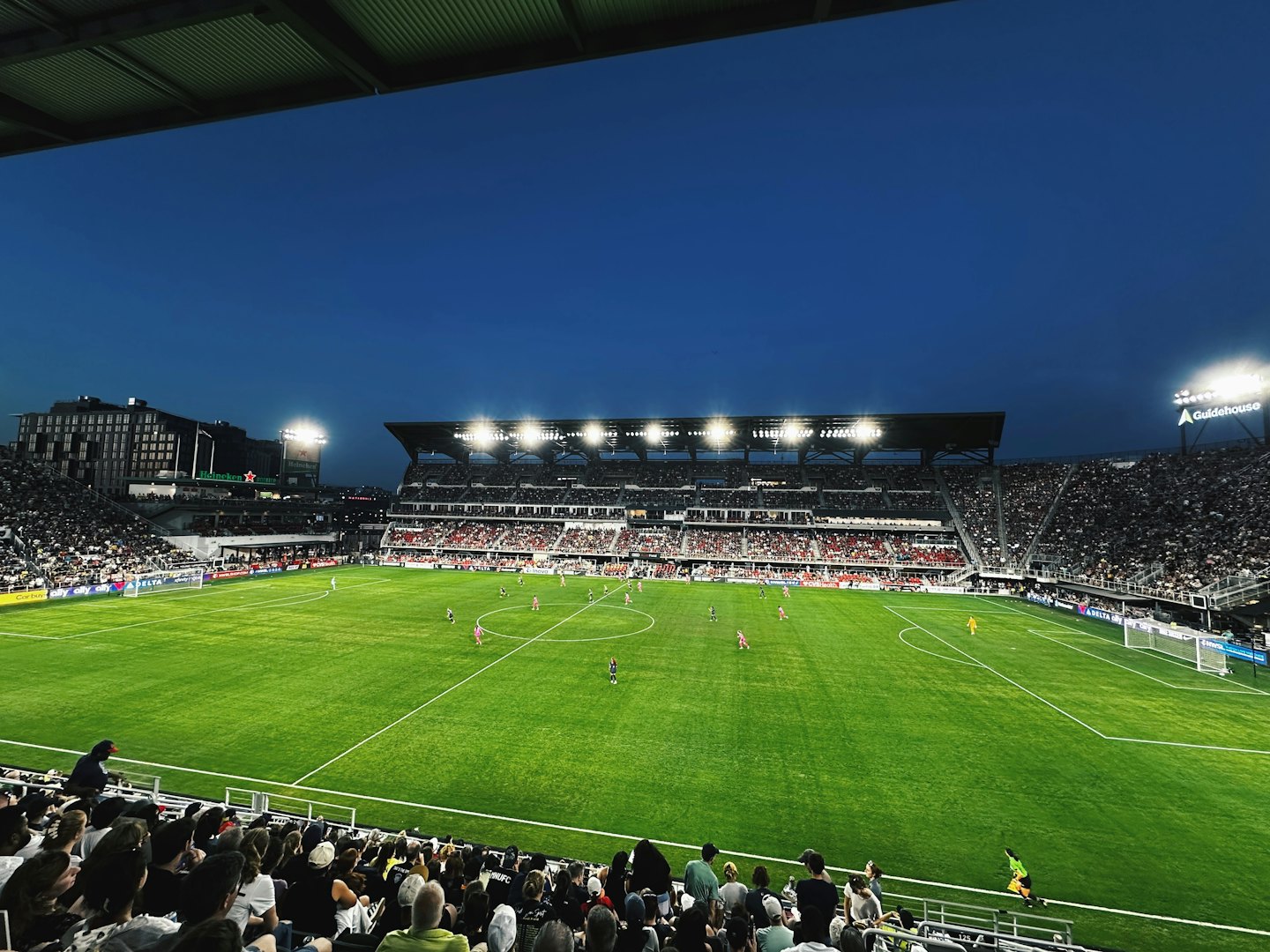 Giocatori di calcio competono sotto le luci dello stadio su un campo verde.