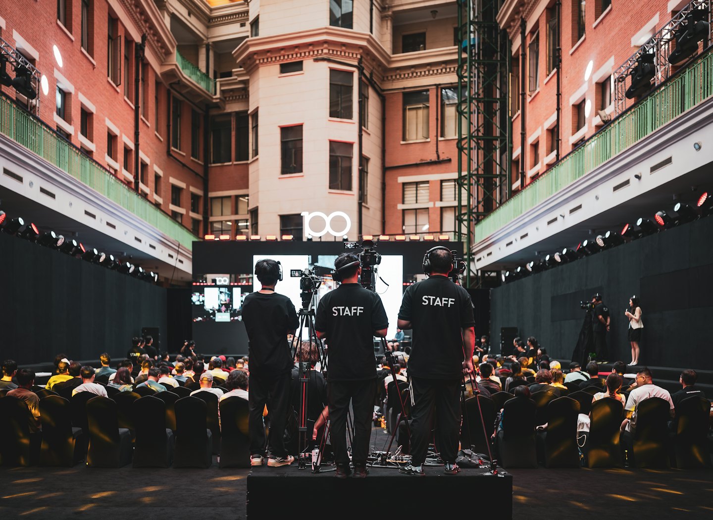 Una troupe televisiva riprende un evento da una piattaforma rialzata.