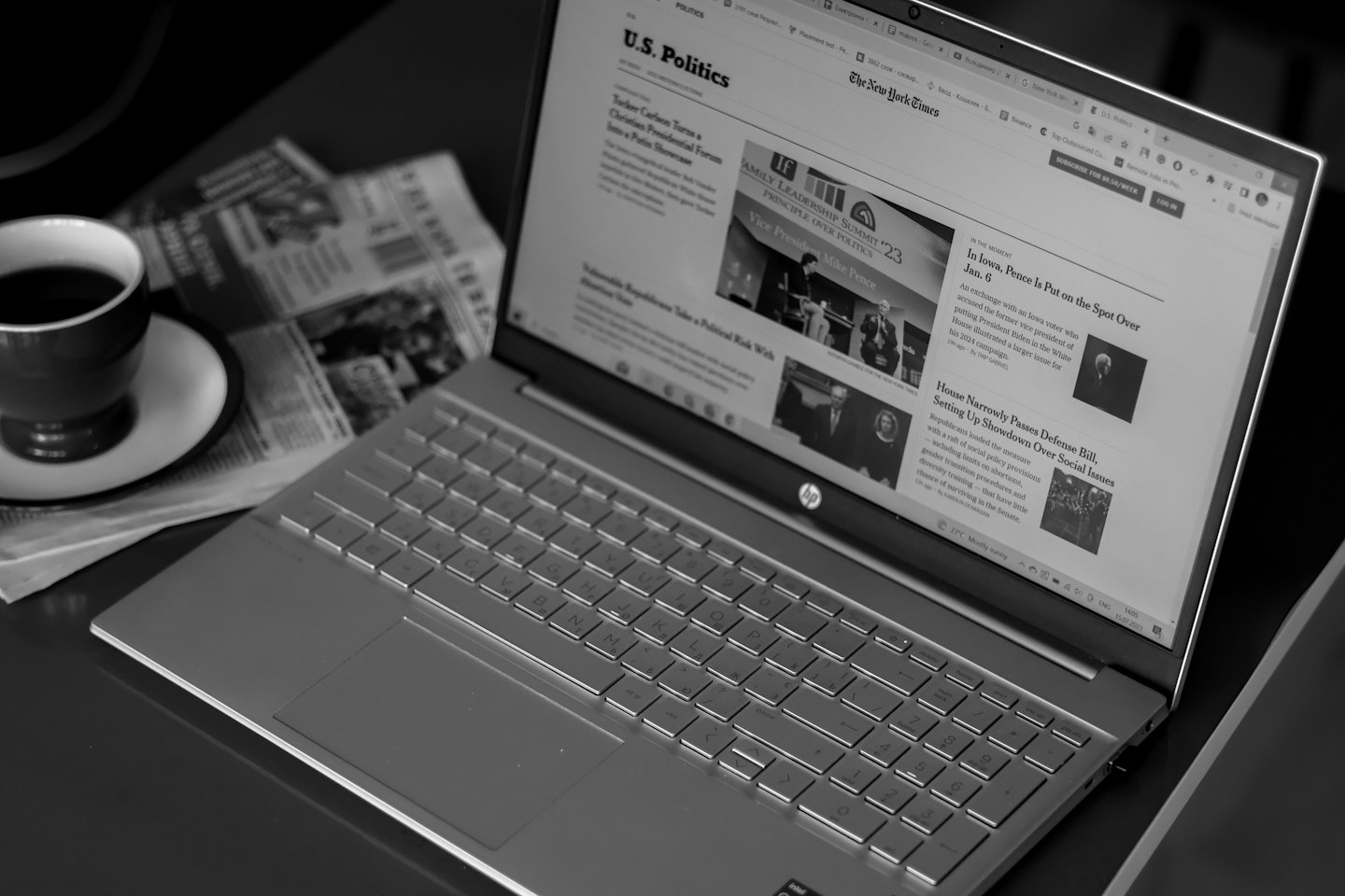 Laptop che mostra articoli di notizie con caffè e giornali sulla scrivania.