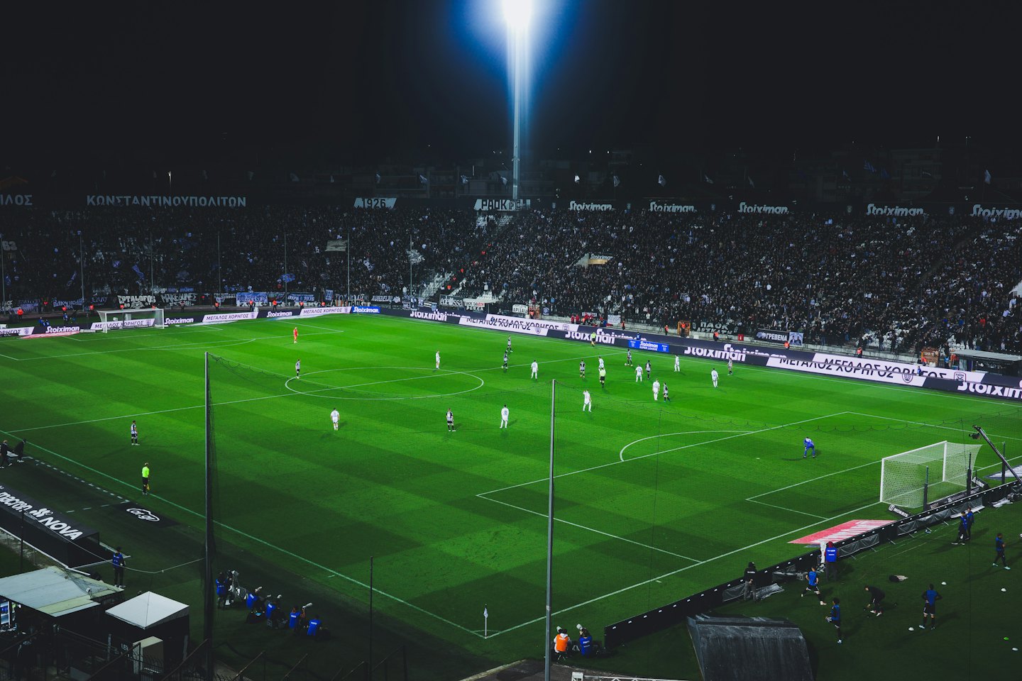 Giocatori di football competono su un campo da stadio verde brillante.